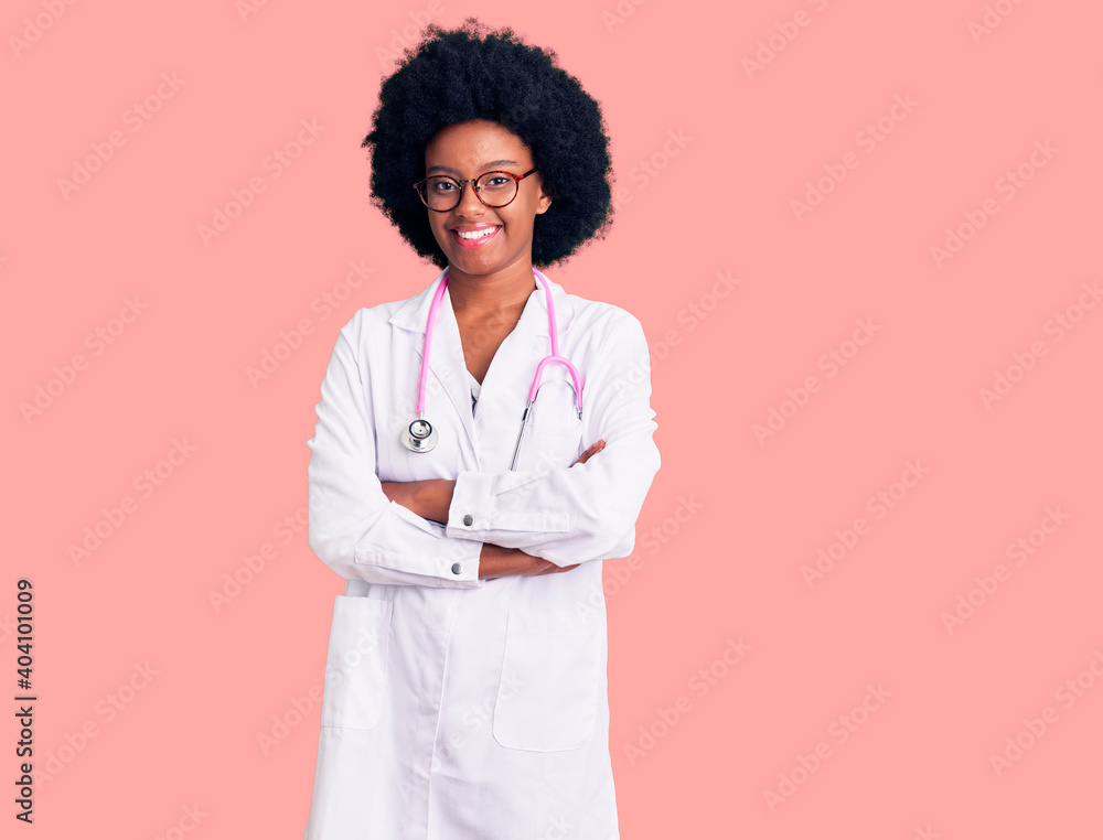 Young african american woman wearing doctor coat and stethoscope happy face smiling with crossed arms looking at the camera. positive person. Young african american woman wearing doctor coat and stethoscope happy face smiling with crossed arms looking at the camera. positive person.