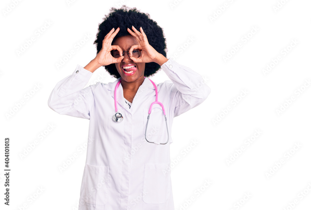 Young african american woman wearing doctor coat and stethoscope doing ok gesture like binoculars sticking tongue out, eyes looking through fingers. crazy expression. Young african american woman wearing doctor coat and stethoscope doing ok gesture like binoculars sticking tongue out, eyes looking through fingers. crazy expression.