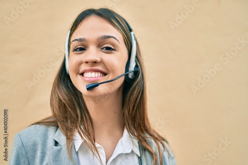 Young latin call center aget girl smiling happy using headset at the city. photo