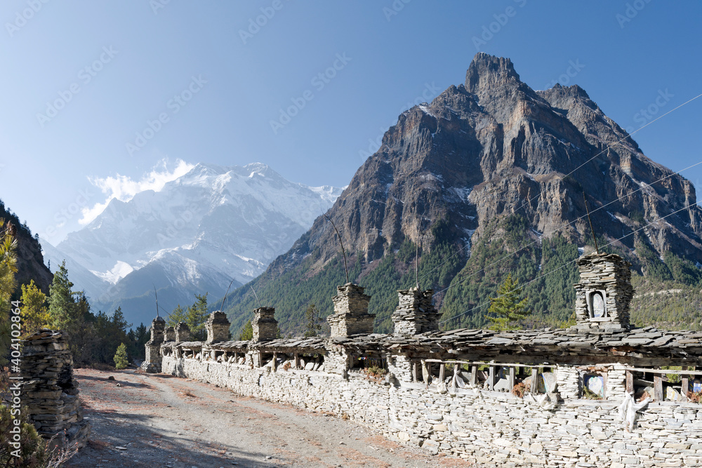 mani-wall-before-the-ascent-to-gyaru-with-annapurna-ii-peak-in-the