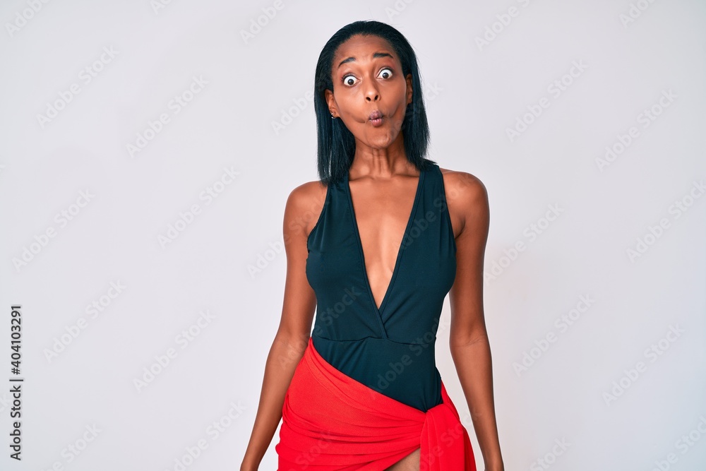 Young african american woman wearing swimsuit making fish face with lips, crazy and comical gesture. funny expression. Young african american woman wearing swimsuit making fish face with lips, crazy and comical gesture. funny expression.