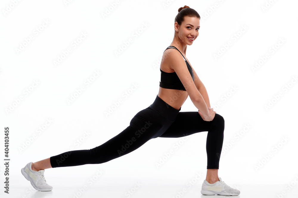 Fit strong fitness woman in sportswear stretching legs on white isolated background. Female sport instructor doing physical exercise Fit strong fitness woman in sportswear stretching legs on white isolated background. Female sport instructor doing physical exercise