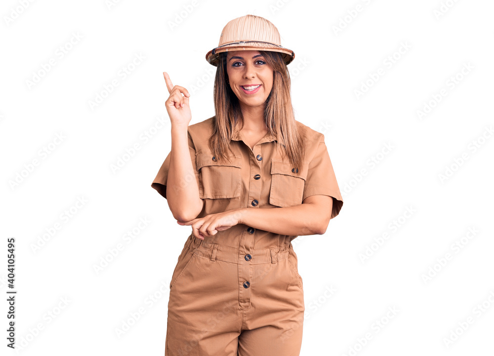 Young beautiful woman wearing explorer hat smiling happy pointing with hand and finger to the side Young beautiful woman wearing explorer hat smiling happy pointing with hand and finger to the side