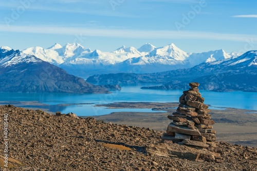 Scenic view to valley with turquoise lakes with blurred snow-capped mountains on background in Los Glaciares National Park,Patagonia,Argentina.Selective focus to cairn in front of. Stone wish pyramid.