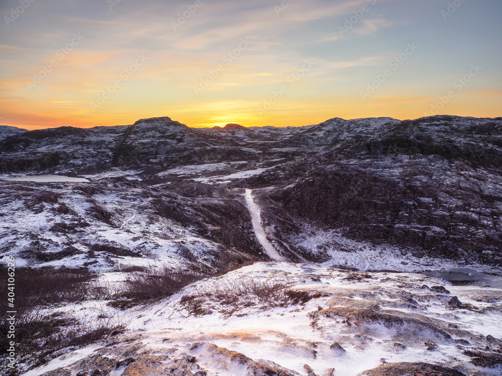 Icy winter road through the tundra hills in Teriberka. Amazing colorful Arctic landscape.
