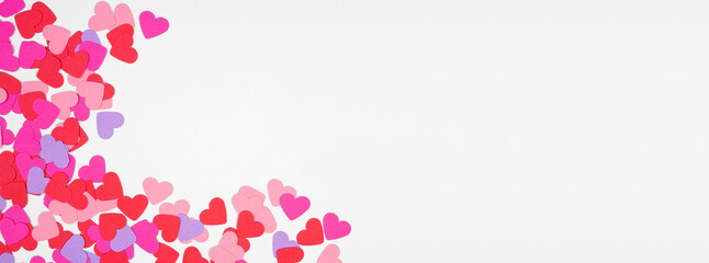 Valentines Day corner border  with paper heart confetti. Overhead view over a white banner background. Copy space.
