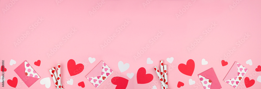 Valentines Day bottom border of heart decorations. Top view over a pink banner background. Copy space.