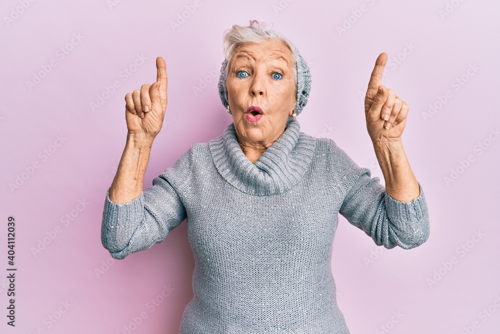 Senior grey-haired woman pointing up with fingers afraid and shocked with surprise and amazed expression, fear and excited face. Senior grey-haired woman pointing up with fingers afraid and shocked with surprise and amazed expression, fear and excited face.