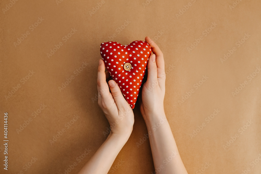 Hands holding red with white polka dot heart. Hands holding red with white polka dot heart.