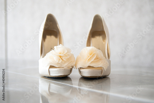 High heel bridal shoes with silk flowers on reflective surface