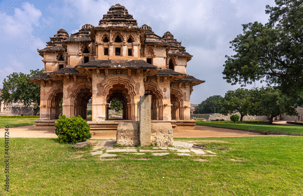 Hampi, Karnataka, India - November 5, 2013: Zanana Enclosure. Brown stone ruinous Lotus Mahal building in green park under blue cloudscape. 