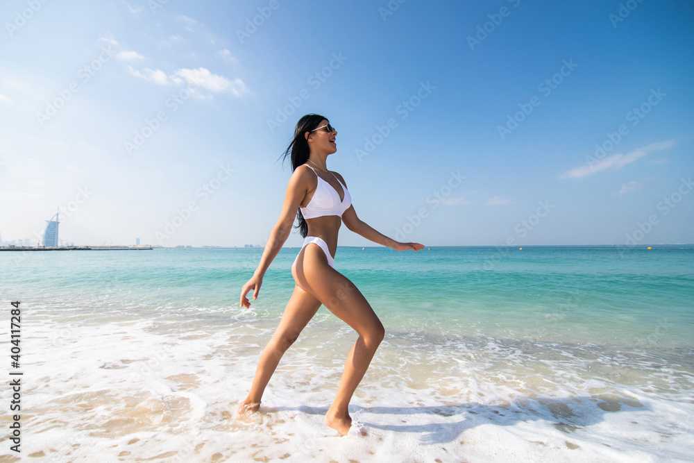 Happy young woman in bikini running on the beach
