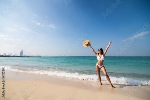 Young woman with arms apart on sand beach and sea background