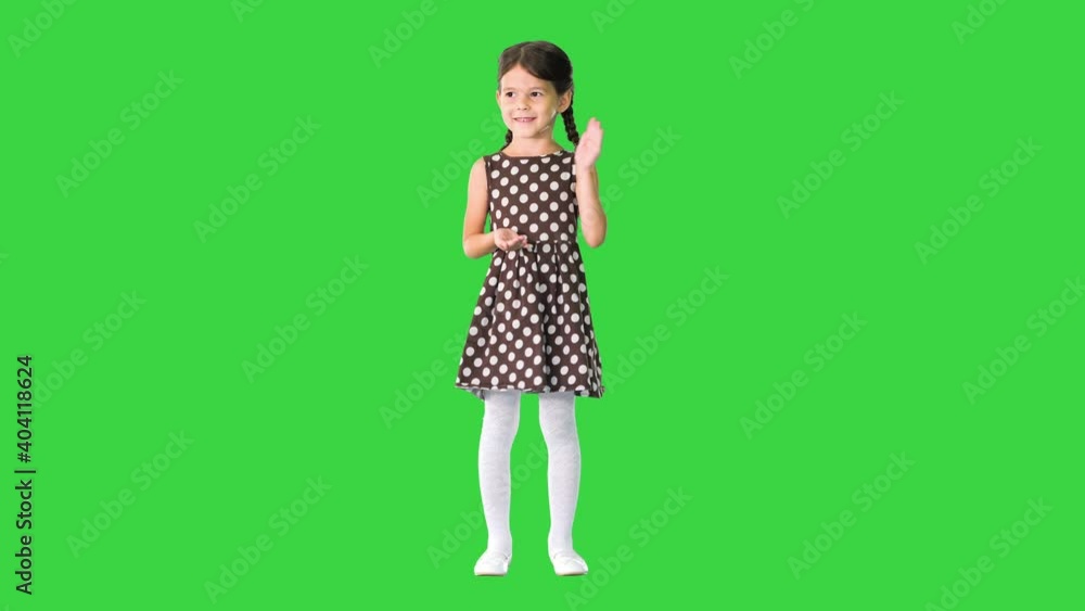 Cute little girl in polka dot dress clapping her hands looking at camera on a Green Screen, Chroma Key. Cute little girl in polka dot dress clapping her hands looking at camera on a Green Screen, Chroma Key.