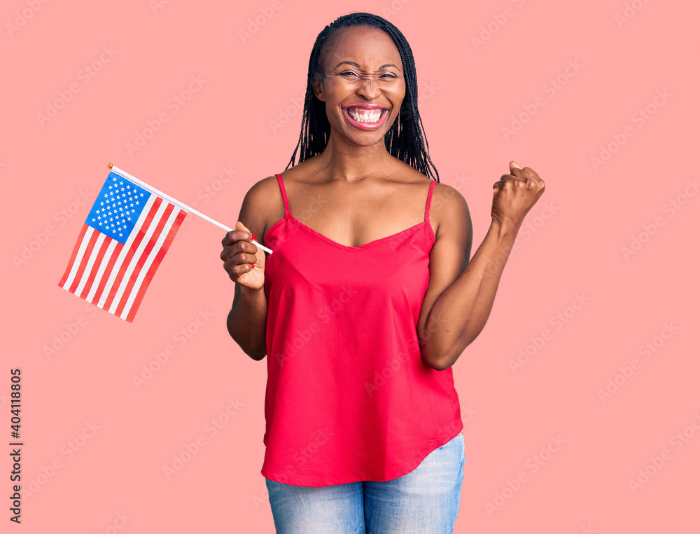 Young african american woman holding united states flag screaming proud, celebrating victory and success very excited with raised arms Young african american woman holding united states flag screaming proud, celebrating victory and success very excited with raised arms