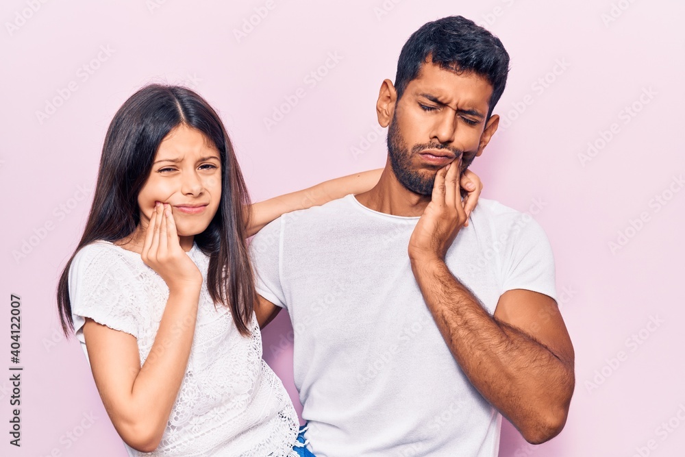 Young father and daughter wearing casual clothes touching mouth with hand with painful expression because of toothache or dental illness on teeth. dentist
