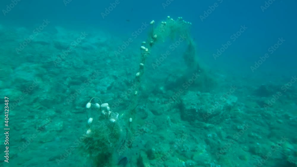 Lost fishing net with buoys lies underwater on the seabed. Problem of ghost gear - any fishing gear that has been abandoned, lost or otherwise discarded. It is the most harmful form of marine debris Lost fishing net with buoys lies underwater on the seabed. Problem of ghost gear - any fishing gear that has been abandoned, lost or otherwise discarded. It is the most harmful form of marine debris