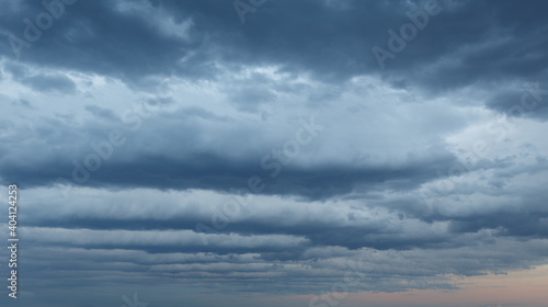 Natural color dramatic dark blue cloudy sky with wavy rippling clouds aligned above horizon, taken with wide angle 35 mm lens for sky replacement