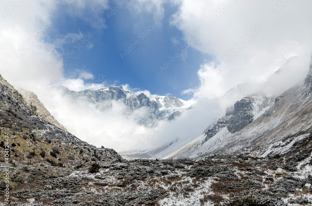 Winter landscape with mountain peaks appearing behind clouds near Yak Kharka, Annapurna Circuit, Nepal