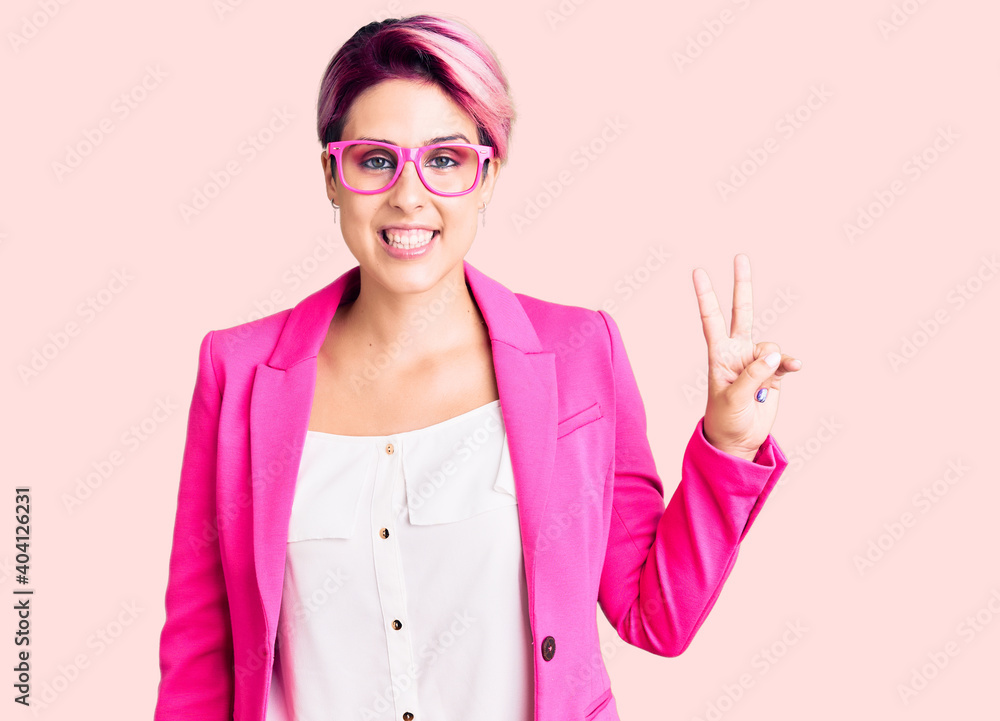 Young beautiful woman with pink hair wearing business jacket and glasses smiling with happy face winking at the camera doing victory sign. number two. Young beautiful woman with pink hair wearing business jacket and glasses smiling with happy face winking at the camera doing victory sign. number two.