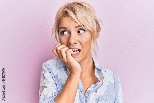 Young blonde girl wearing casual clothes looking stressed and nervous with hands on mouth biting nails. anxiety problem.