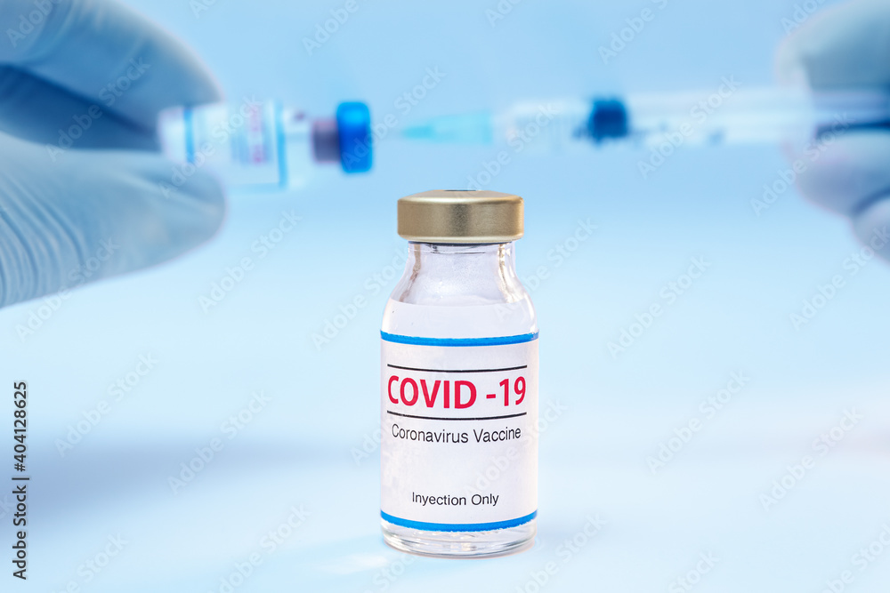 Bottle of coronavirus vaccine and doctor hands with syringe background. Bottle of coronavirus vaccine and doctor hands with syringe background.