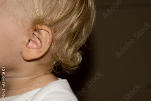 close up view of ear little white girl with curly hair and place for your text,kids ear,shape of humans organ of sense side view