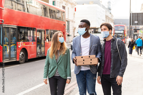Photography Happy friends wearing masks with takeaway pizza in London during lockdown - Mult