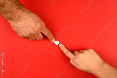 Valentine's Day background. hands of a couple giving their heart on a red background. Valentine's Day concept. Flat view, top view, copy space