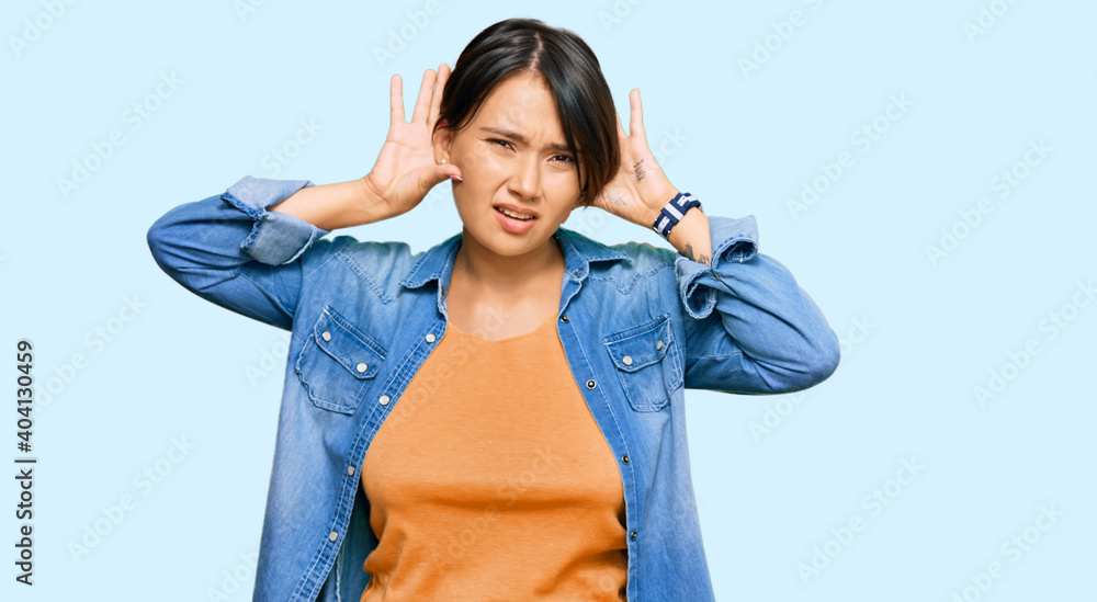 Young beautiful hispanic woman with short hair wearing casual denim jacket trying to hear both hands on ear gesture, curious for gossip. hearing problem, deaf Young beautiful hispanic woman with short hair wearing casual denim jacket trying to hear both hands on ear gesture, curious for gossip. hearing problem, deaf