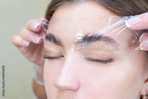 Foto Beautiful young woman got correction of eyebrows in a beauty salon