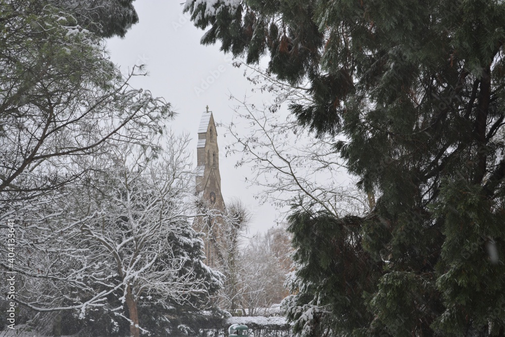 Winter landscape on a snowy day  in Albert park, Abingdon, Oxfordshire, Great Britain.  A view on the bell tower of St Michael and All Angels' Church from the park. 