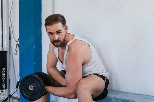 Man making biceps with a dumbbell. Fitness in gym, sport and healthy lifestyle concept