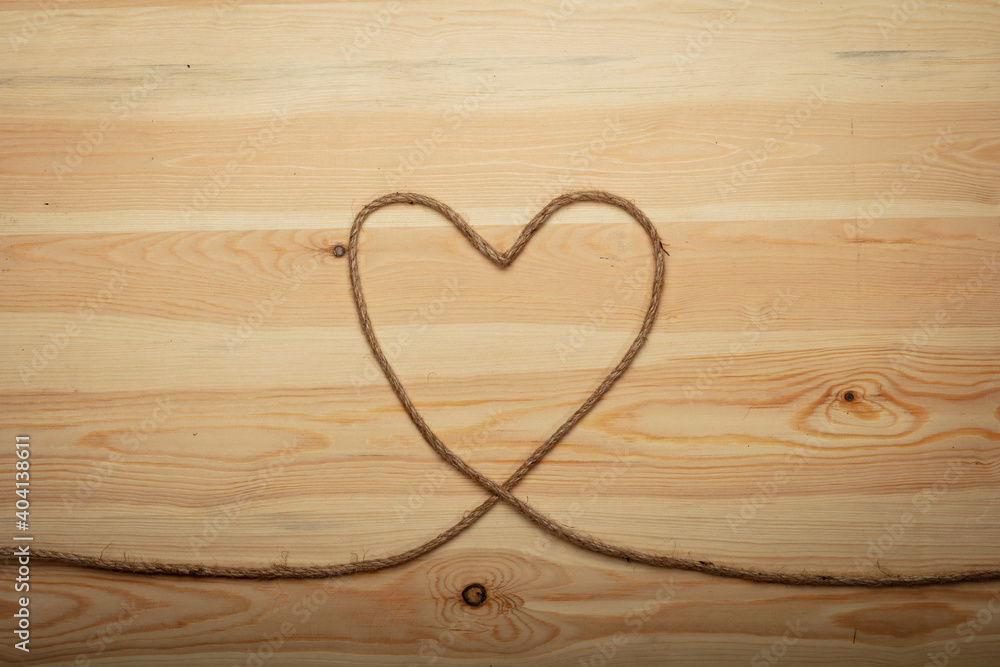 Valentine's day concept with heart made from woolen rope on wooden background.