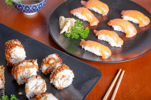 Salmon sushi typical of Japanese cuisine on black plate, natural light inside restaurant