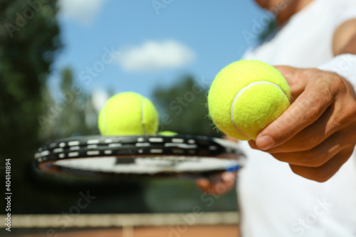 Sportsman with racket and tennis balls at court, closeup © New Africa