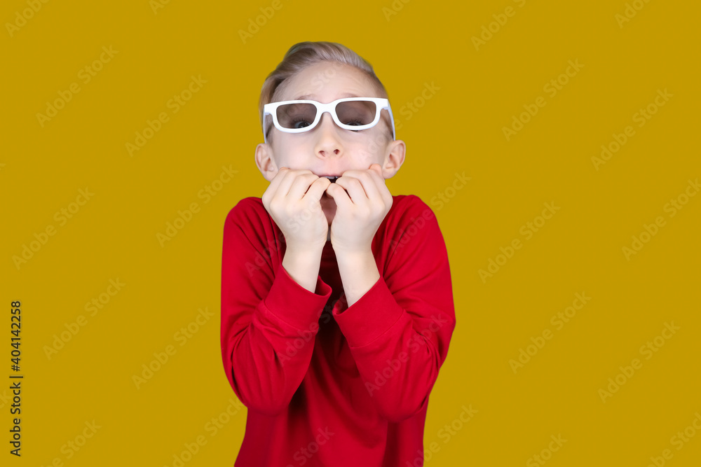 a child in children's 3D glasses bites his nails in surprise a child in children's 3D glasses bites his nails in surprise
