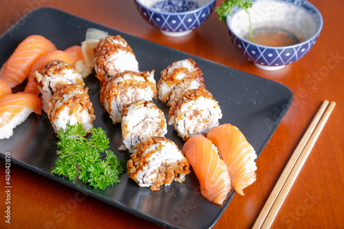 Salmon sushi typical of Japanese cuisine on black plate, natural light inside restaurant