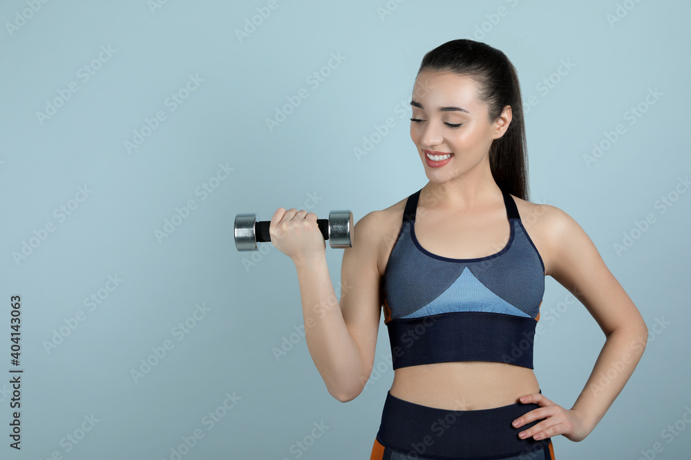 Woman with dumbbell as girl power symbol on light grey background, space for text. 8 March concept Woman with dumbbell as girl power symbol on light grey background, space for text. 8 March concept