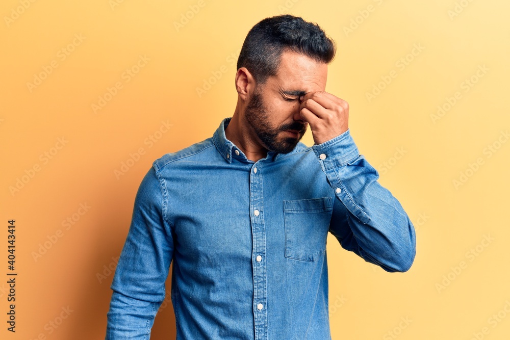 Young hispanic man wearing casual clothes tired rubbing nose and eyes feeling fatigue and headache. stress and frustration concept. Young hispanic man wearing casual clothes tired rubbing nose and eyes feeling fatigue and headache. stress and frustration concept.