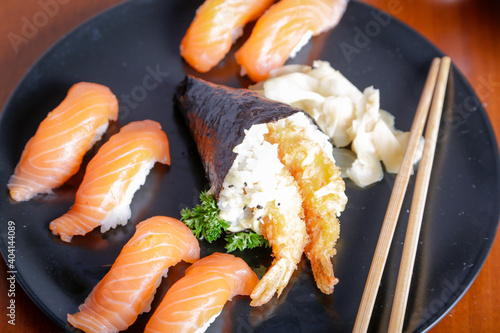 Salmon sushi typical of Japanese cuisine on black plate, natural light inside restaurant