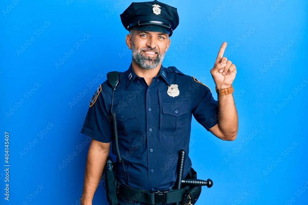 Middle age handsome man wearing police uniform with a big smile on face, pointing with hand finger to the side looking at the camera. Middle age handsome man wearing police uniform with a big smile on face, pointing with hand finger to the side looking at the camera.