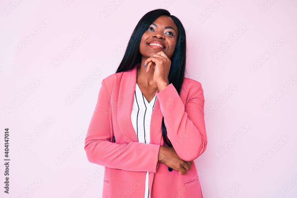 Young african american woman wearing business clothes looking confident at the camera with smile with crossed arms and hand raised on chin. thinking positive. Young african american woman wearing business clothes looking confident at the camera with smile with crossed arms and hand raised on chin. thinking positive.