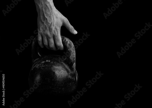 The athlete strong hand takes the kettlebell. Weight-lifting. A large sports kettlebell and an athlete arm.