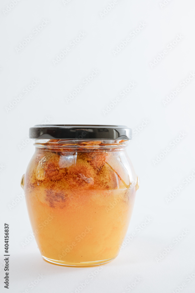 Small jar with honey and nuts. Glass jar with black lid on a white background Small jar with honey and nuts. Glass jar with black lid on a white background