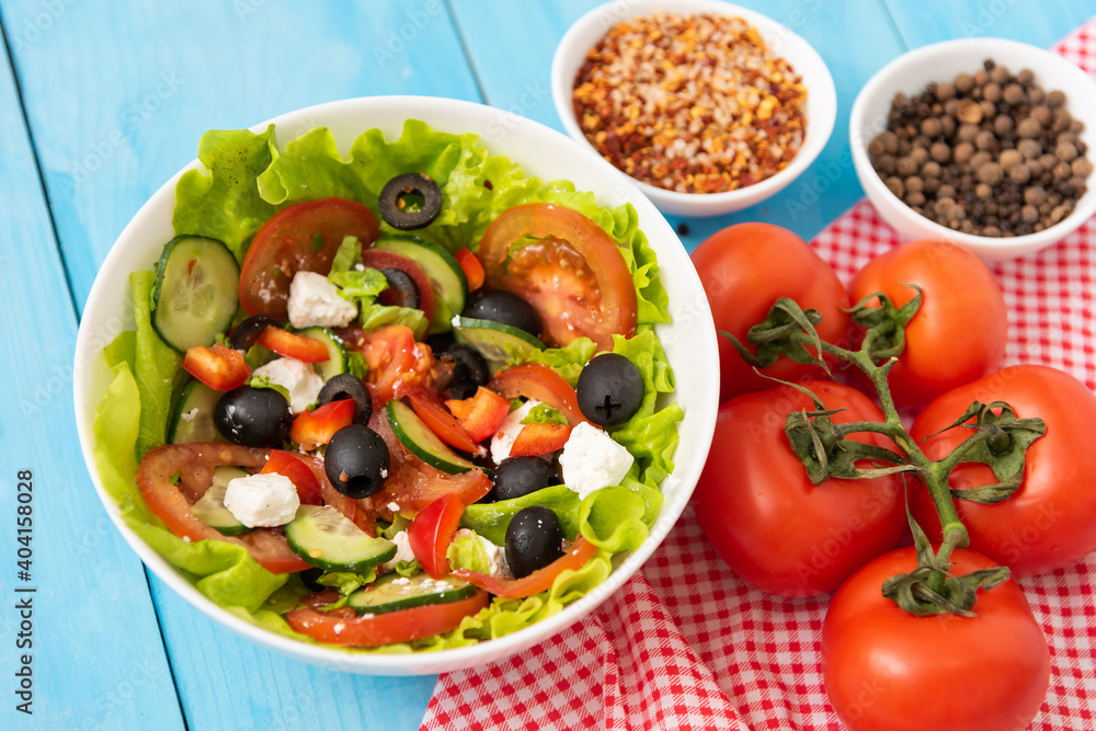 Greek salad with olives, feta cheese and fresh vegetables on a wooden blue table. Greek salad with olives, feta cheese and fresh vegetables on a wooden blue table.