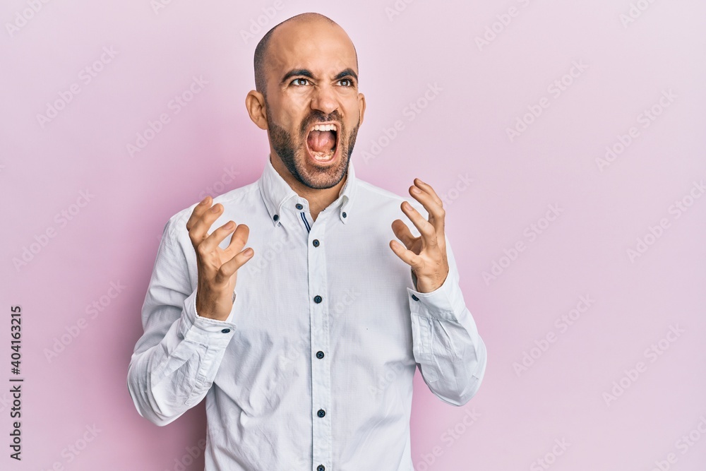 Young hispanic man wearing casual clothes crazy and mad shouting and yelling with aggressive expression and arms raised. frustration concept. Young hispanic man wearing casual clothes crazy and mad shouting and yelling with aggressive expression and arms raised. frustration concept.