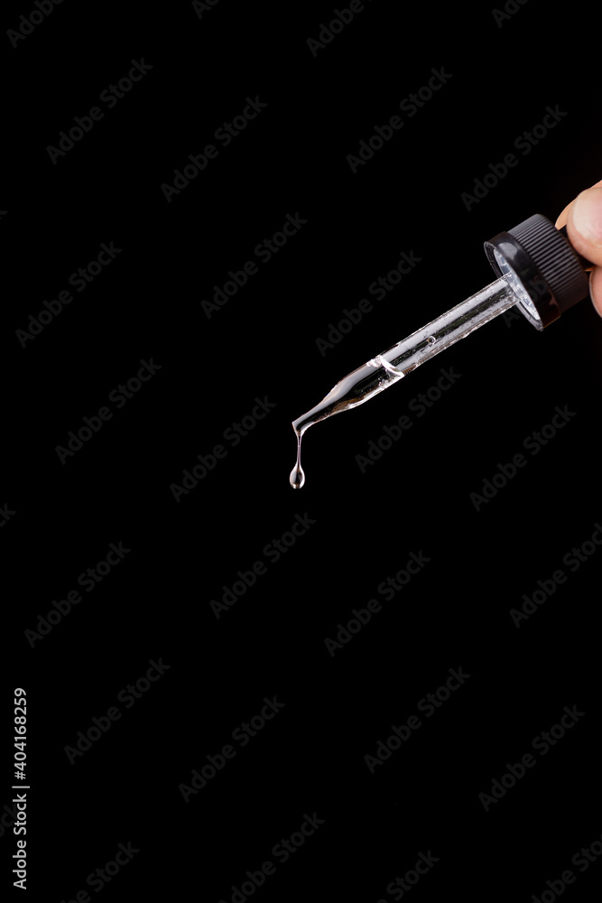 The falling drop of transparent liquid isolated on the black background The falling drop of transparent liquid isolated on the black background
