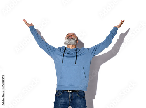 Obraz na plátně Stylish gray-haired bearded hipster man showing hallelujah gesture, looking up
