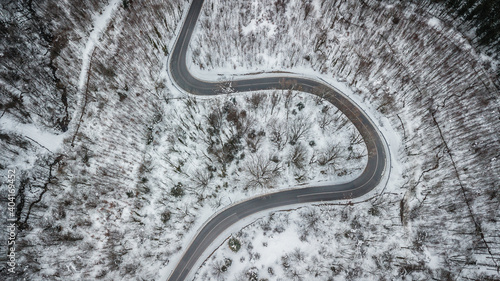 aerial view of alpine road crossing a forest